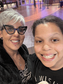 a woman wearing glasses stands next to a girl wearing a black shirt that says " i wish "