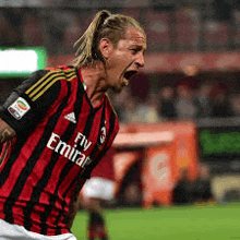 a soccer player wearing a fly emirates jersey is screaming on the field