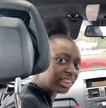 a woman is sitting in the driver 's seat of a car looking at the camera .