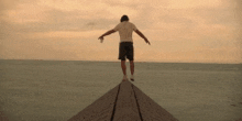 a man is standing on a pier overlooking the ocean with his arms outstretched .