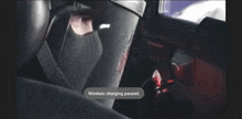 a man in a mask is sitting in a car and wireless charging has paused