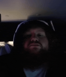 a man with a beard is wearing a hooded jacket and sunglasses