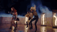 a group of women are dancing on a stage in front of flames