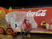 a family poses in front of a coca cola display