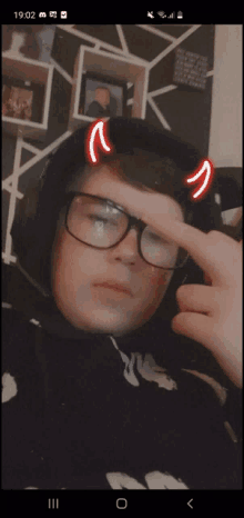 a young man wearing glasses and headphones has devil horns on his head