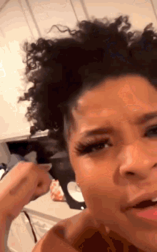 a woman with curly hair is getting her hair done in a kitchen while talking on a cell phone .