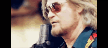 a man singing into a microphone with sunglasses on