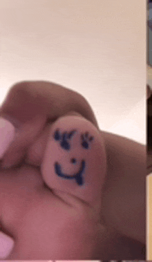 a close up of a finger with a smiley face drawn on it .