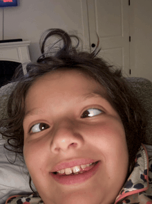 a little girl laying on a couch with a netflix tv behind her