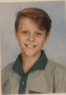 a young boy wearing a green and white shirt is smiling for a picture .