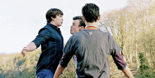 three young men are standing in a field with trees in the background and one of them has a t-shirt with a lion on it