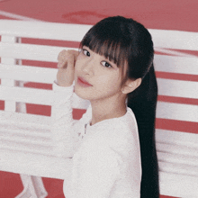 a girl with long black hair is sitting on a bench