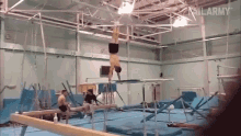 a man is doing a handstand on a balance beam in a gym with the word failarmy on the bottom