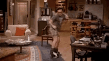 a man is dancing in a living room in front of a couch and a table .