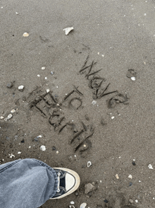 a person standing on a sandy beach with the words " wave " written on the sand