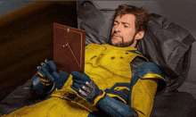 a man in a yellow and blue suit is laying on a bed reading a picture frame