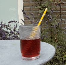 a glass of red liquid with a yellow and white striped straw