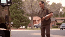 a man in a ups uniform is standing in front of a truck on the side of the road .