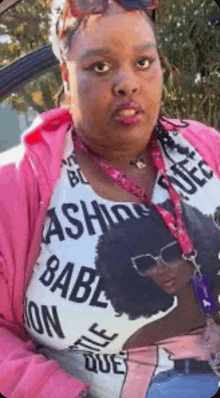 a woman wearing a pink jacket and a white shirt with the word babe on it .