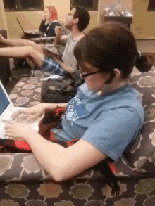 a woman sitting on a couch with a laptop and wearing a shirt that says ' i love oceans '