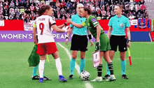 a group of women playing soccer on a field with a sign that says women 's pean in the background .