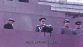 a man stands in front of a microphone with the words who defended the honour freedom and independence of our motherland on the bottom