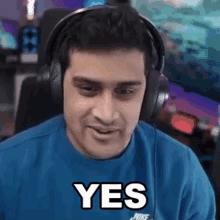 a man wearing headphones and a blue shirt that says yes