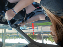 a woman is driving a car with the steering wheel turned upside down