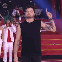 a man in a black tank top stands on a stage in front of a sign that says " black friday "