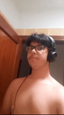 a shirtless man wearing headphones and glasses .