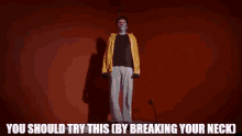 a man in a yellow jacket and white pants is standing in front of a microphone with the words you should try this by breaking your neck