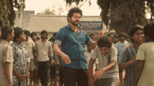 a man in a blue shirt stands in front of a group of children and a sign that says ' chennai picture house '