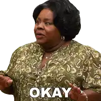 a woman in a paisley shirt says okay with her hands outstretched