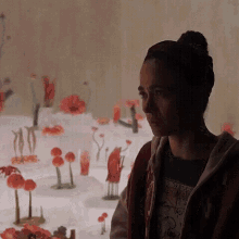 a woman stands in front of a display of flowers and wears a shirt that says ' new york '