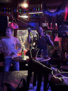 a budweiser sign hangs above a man singing into a microphone