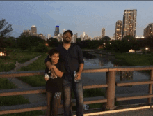 a man and a boy are standing on a bridge and the boy is wearing a ny shirt