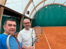 two men holding tennis rackets on a court