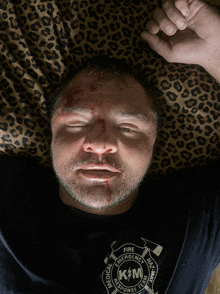 a man laying on a leopard print blanket with a shirt that says fire emergency medical response team