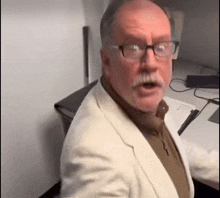 a man with a mustache and glasses is sitting at a desk