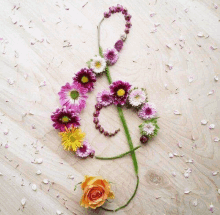 a treble clef made out of flowers on a wooden table .