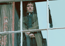 a man is looking out of a window with a reflection of himself