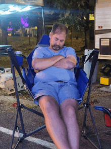 a man in a blue shirt is sleeping in a chair