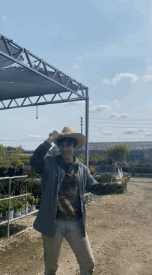 a man wearing a cowboy hat stands in front of a shed