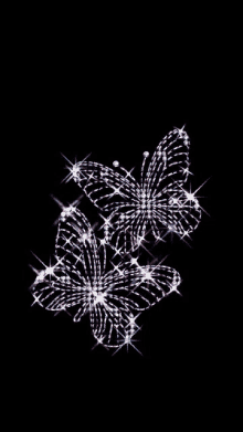 two butterflies made of rhinestones on a black background .