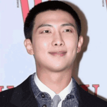 a man with a shaved head is wearing a suit and tie and smiling