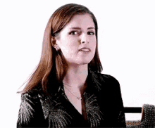a woman wearing a black shirt and a necklace is sitting in front of a microphone and making a funny face .