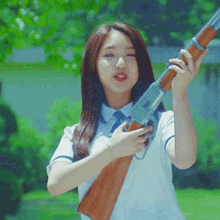 a woman in a white shirt and tie holds a rifle