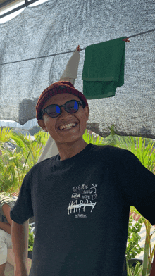 a man wearing sunglasses and a black t-shirt that says happy