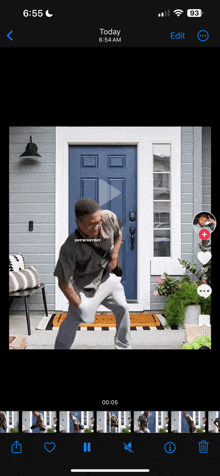 a phone screen shows a video of a man dancing in front of a door