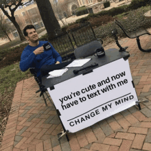 a man is sitting at a table with a sign that says change my mind